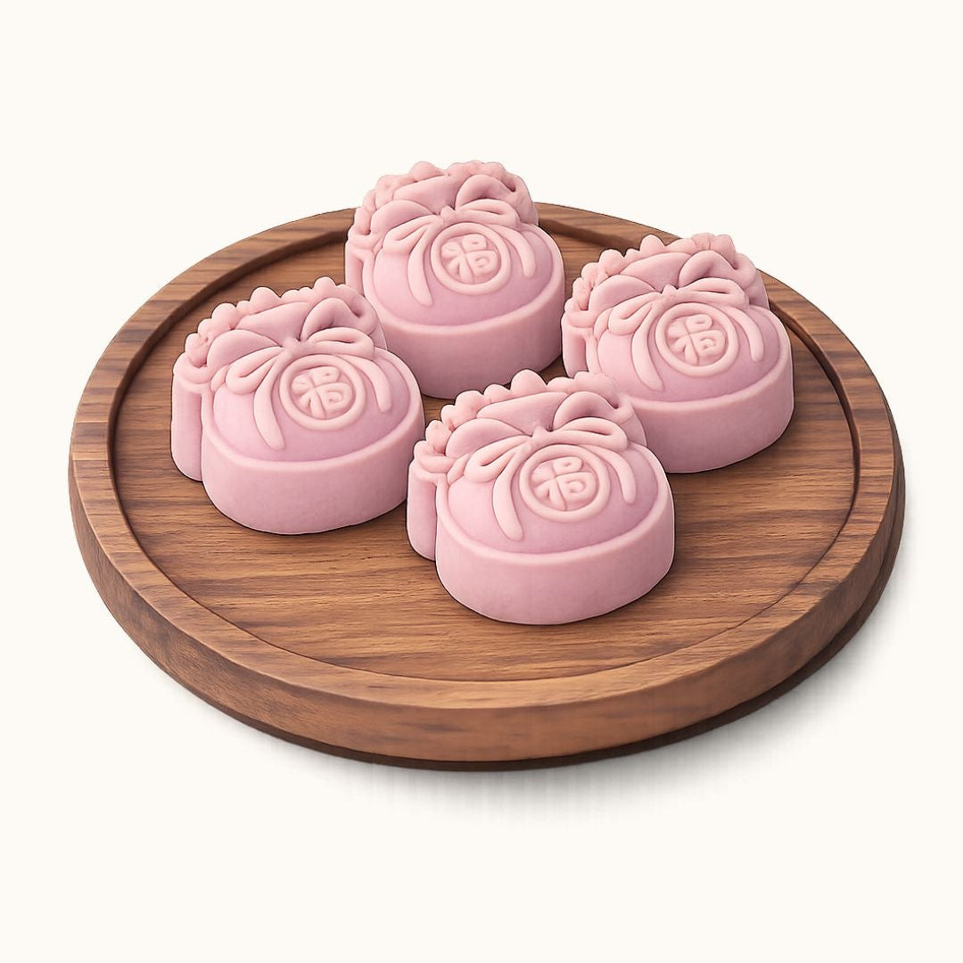 Four pink mooncakes with embossed floral designs and Chinese characters, arranged on a round wooden tray against a light cream background.