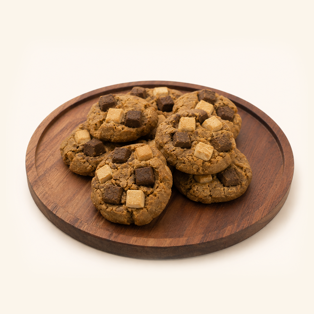 Five chocolate chip cookies with dark and milk chocolate chunks, arranged on a round wooden serving board against a clean off-white background.
